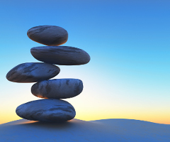 3D render of balancing pebbles on sand against a sunset sky